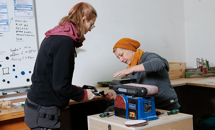 Zwei junge Frauen arbeiten an einer Schleifmaschine