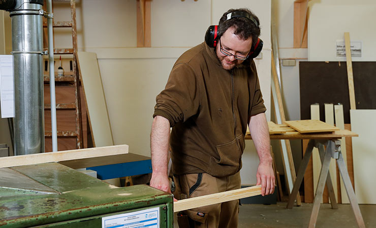 Ein Mann arbeitet in der Werkstatt mit Holz